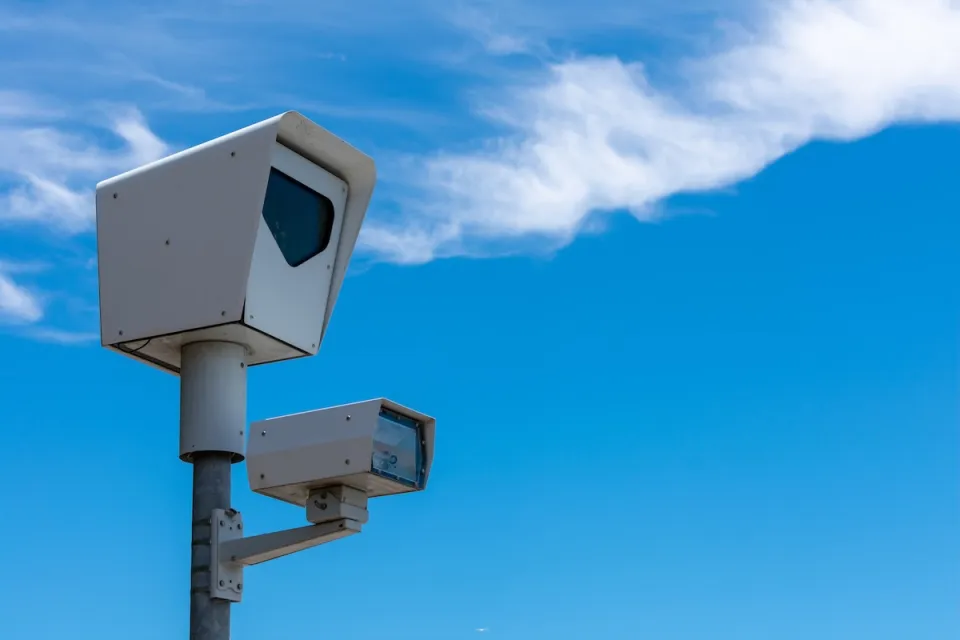 Close-up of speed camera against blue sky.